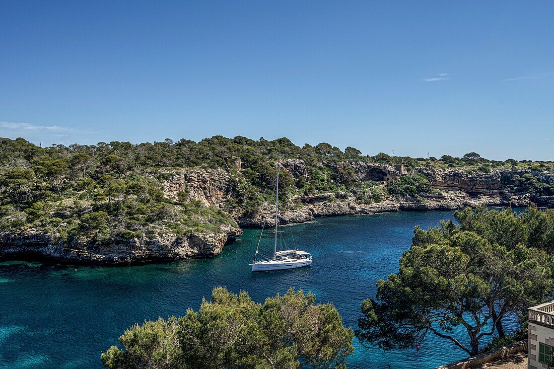 Entry of a yacht into the rocky bay of Cala Figuera, Santanyi, Mallorca, Spain
