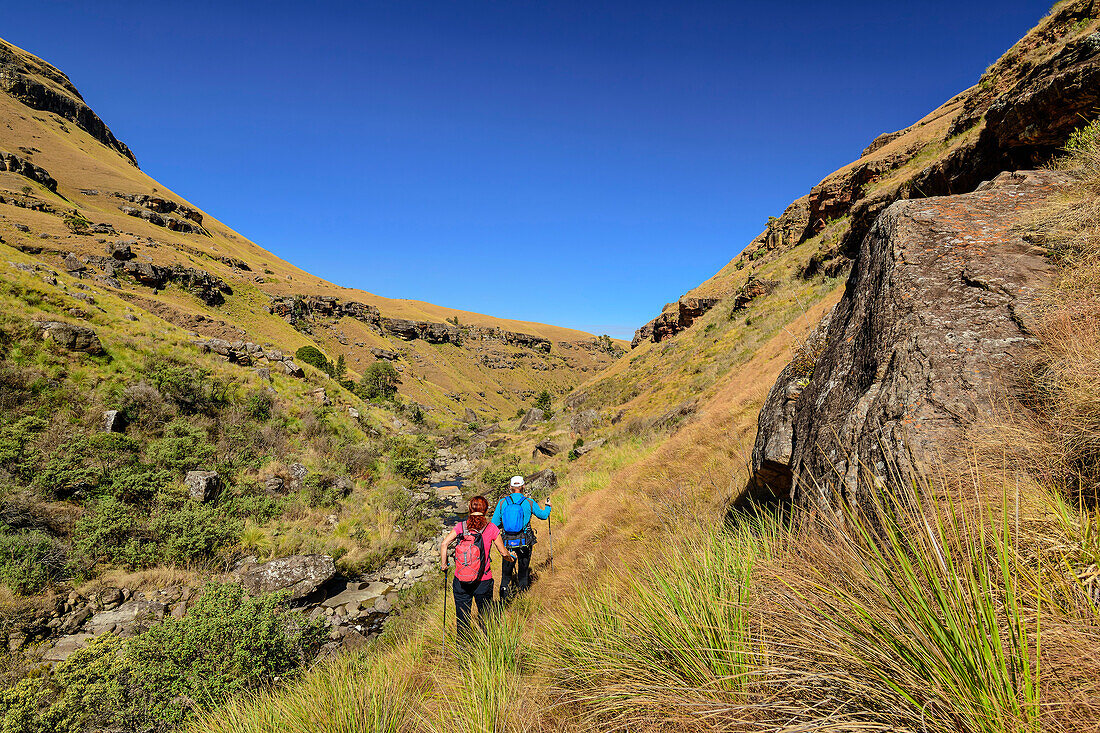 Man and woman hiking to Ash Cave, Lotheni, Drakensberg Mountains, Kwa Zulu Natal, Maloti-Drakensberg UNESCO World Heritage Site, South Africa