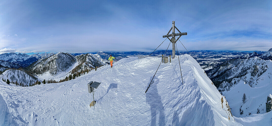 Panorama mit Frau auf Skitour am Gipfelkreuz des Schwarzkogel, Karawanken, Kärnten, Österreich