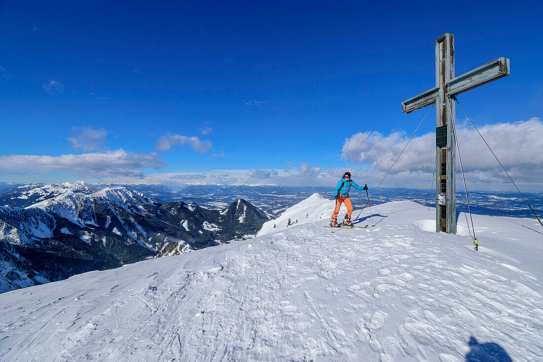 Woman on a ski tour at the summit cross of Kosiak, Kosiak, Rosental, Karawanken, Carinthia, Austria