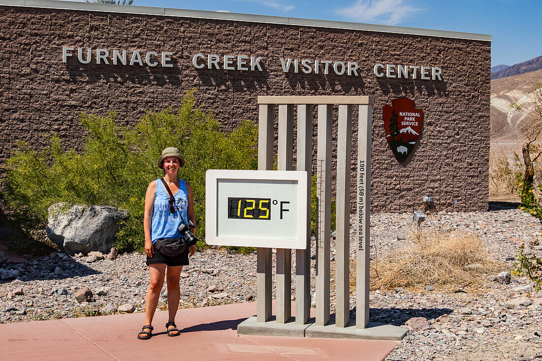 Eine Touristin am berühmten Thermometer am Furnace Creek im Death Valley bei weit über 120 Grad Fahrenheit, Kalifornien, USA