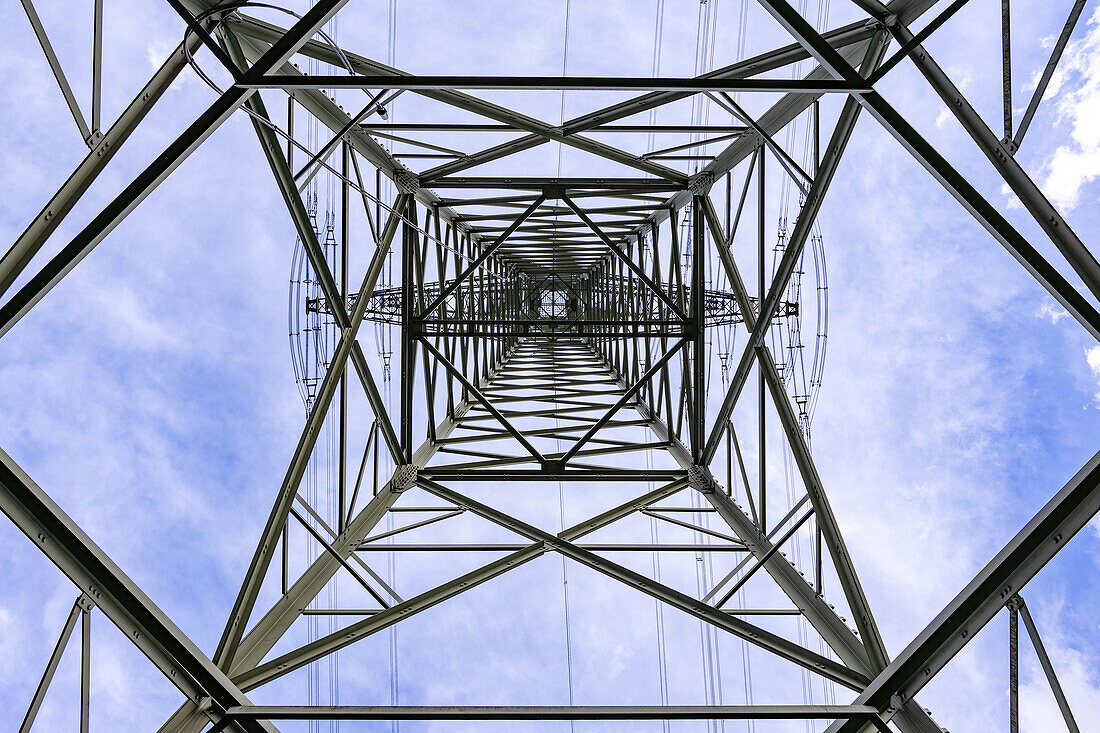 Strommast Konstruktion aus Stahl mit vielen Stromleitungen zum Transport von Strom direkt von unten gegen den Himmel fotografiert