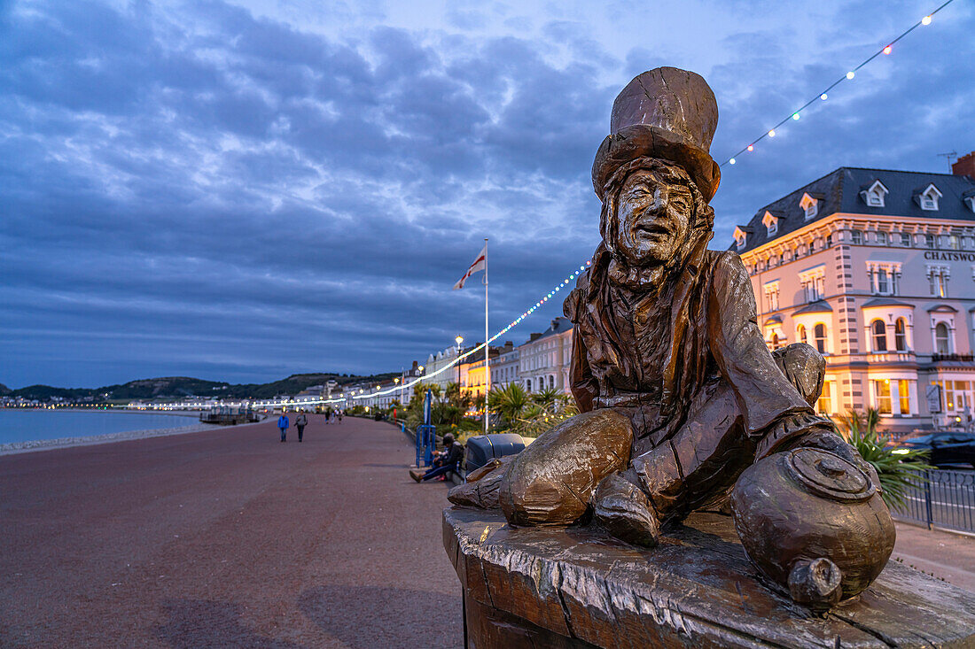 Skulptur des Mad Hatter oder Der verrückte Hutmacher aus Alice im Wunderland auf der Promenade des Seebad Llandudno in der Abenddämmerung, Wales, Großbritannien, Europa