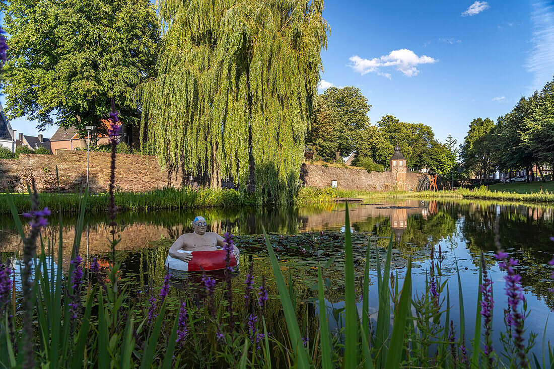 Frog pond with sculpture Paul, the swimming tire man and the city wall with watchtower in Rees, Lower Rhine, North Rhine-Westphalia, Germany, Europe