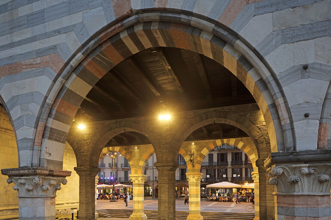 View through the arcades of the Broletto onto cafe house terraces on Via Caio Plinio Secondo, Como, Lake Como, Lombardy, Italy