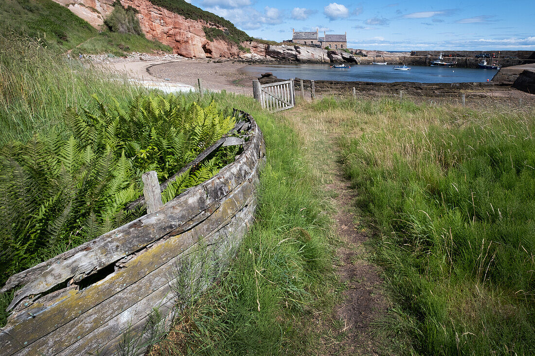 View of an abandoned harbor with old wooden boat in the foreground, East Lothian, Scotland, United Kingdom