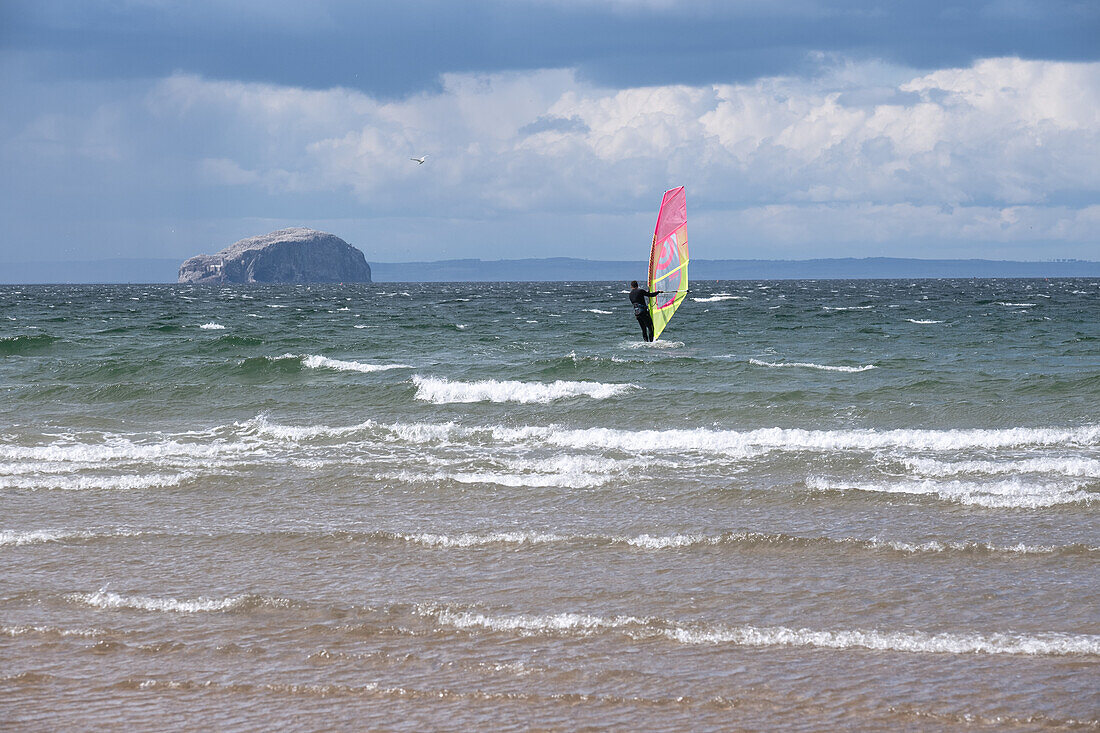 Surfers in front of Bass Rock in the Scottish Atlantic, Dunbar, East Lothian, Scotland, United Kingdom