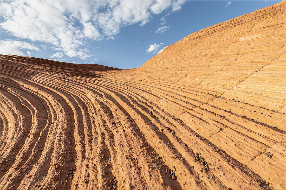 Rock lines on yellow rock lead into the picture towards the blue sky