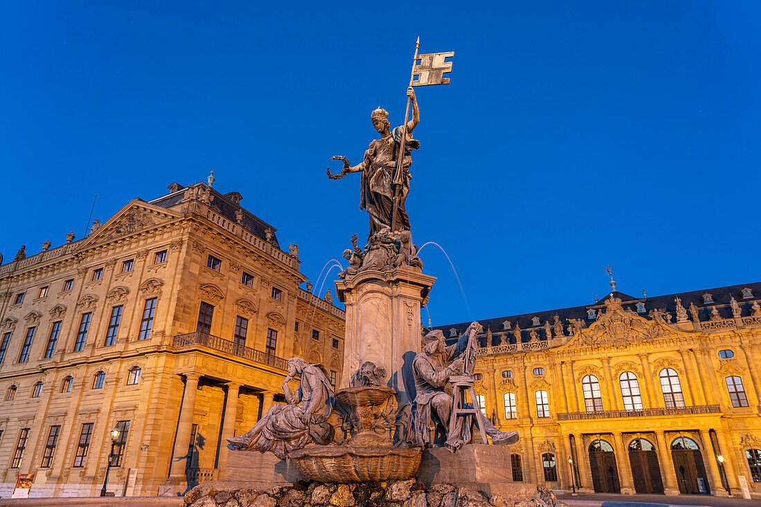 Frankoniabrunnen mit Walther von der Vogelweide und Tilman Riemenschneider vor der Würzburger Residenz in der Abenddämmerung, Würzburg, Bayern, Deutschland  