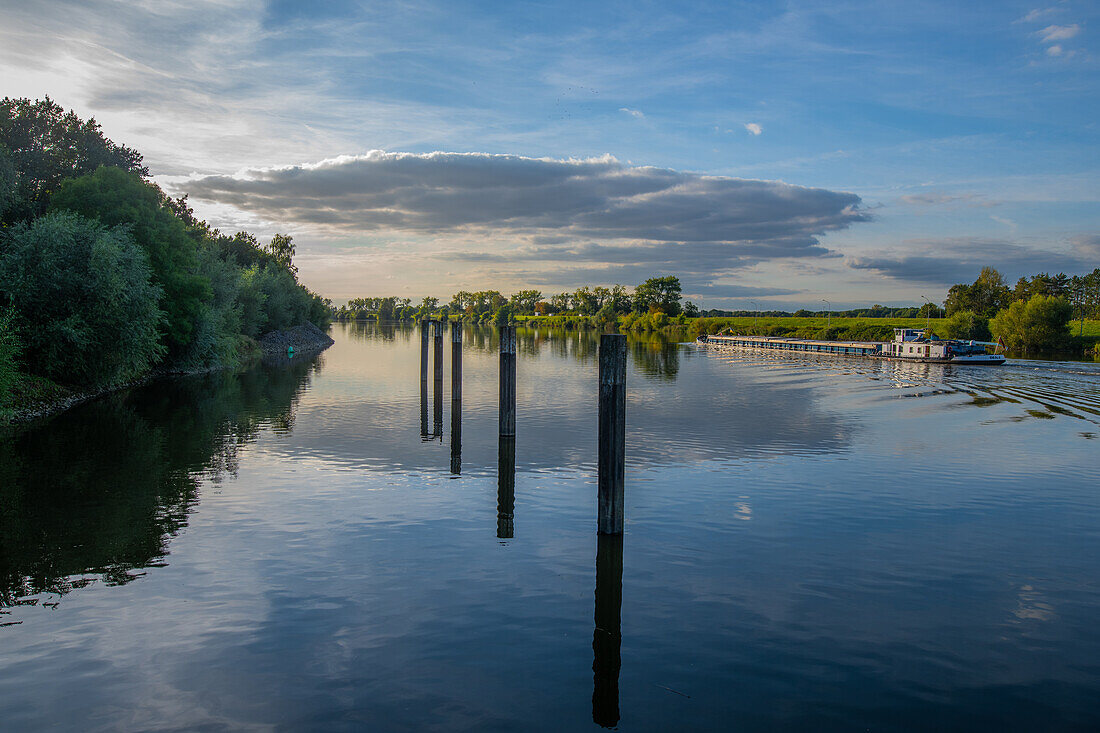 A barge leaves the Geesthard lock canal towards Hamburg in the evening light, Schleswig-Holstein, Germany