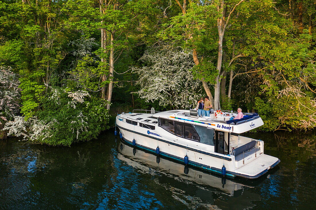 Aerial view of a Le Boat Horizon 4 houseboat moored to an island on the River Thames near Cliveden National Trust, with people preparing a barbecue dinner on deck, near Maidenhead, Berkshire, England, United Kingdom