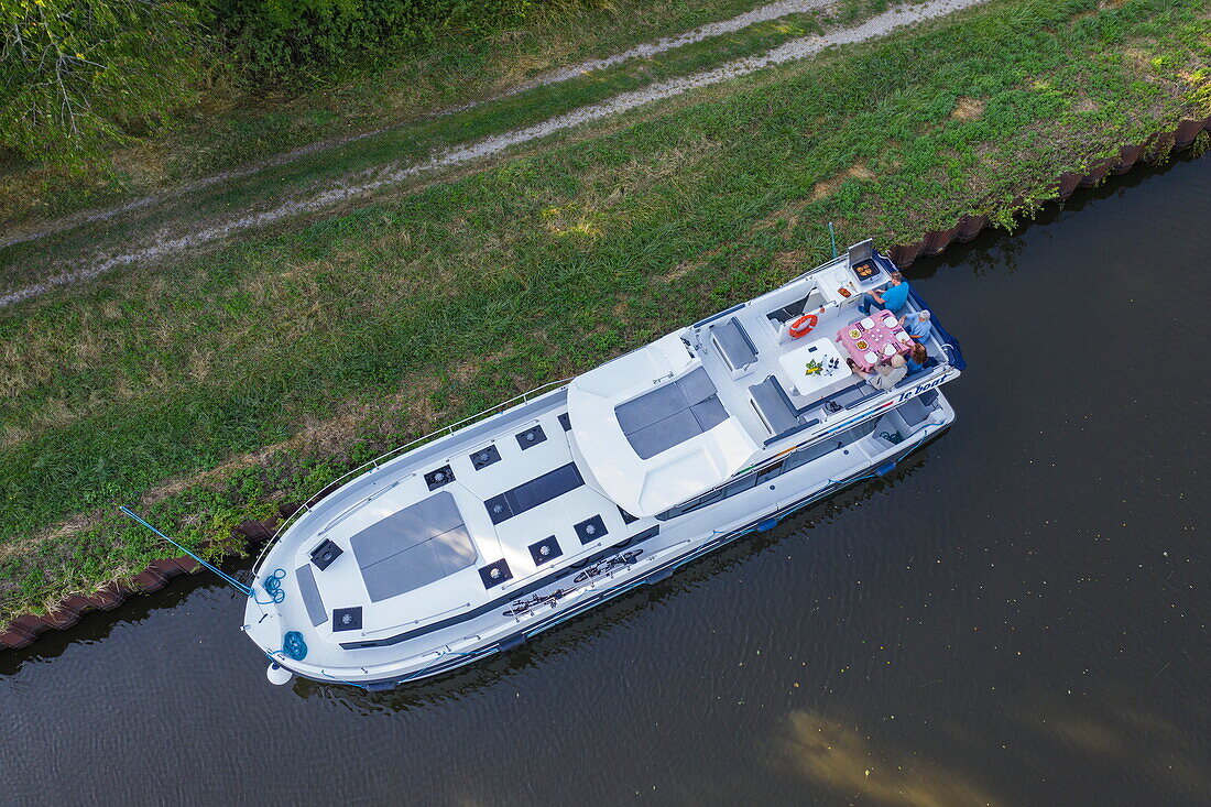 Aerial view of friends enjoying a barbecue dinner on deck of a Le Boat Horizon 5 houseboat moored on the Canal de la Marne au Rhin, Hesse, Moselle, France