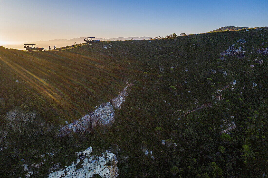 Aerial view and silhouette of Grootbos 4WD vehicles on a mountain ridge at sunset, Grootbos Private Nature Reserve, Western Cape, South Africa