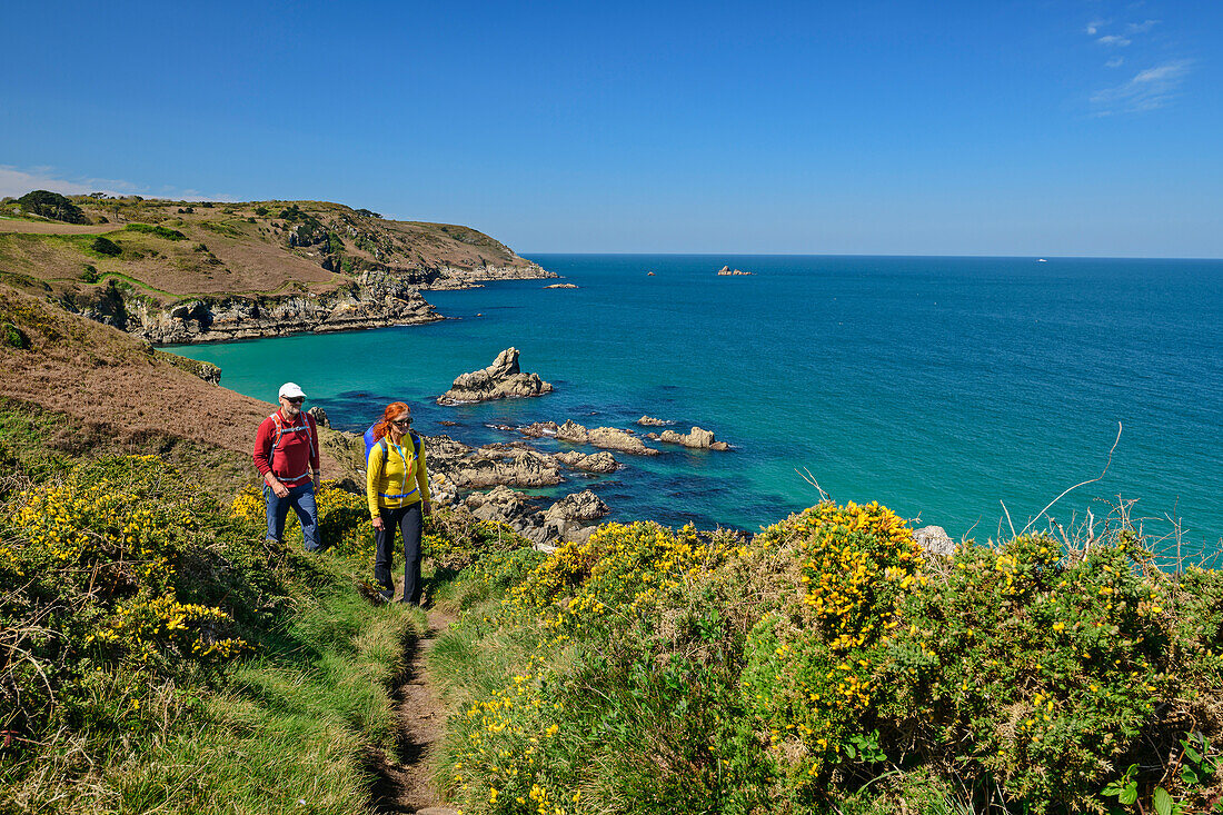 Mann und Frau wandern auf dem Zöllnerweg am Cap Sizun mit Meer und Felsinseln im Hintergrund, Cap-Sizun, GR 34, Zöllnerweg, Bretagne, Frankreich