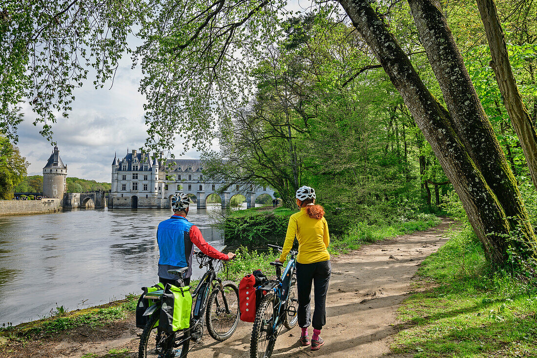 Man and woman cycling looking at the Château de Chenonceau, Loire Castles, Loire Valley, UNESCO World Heritage Site Loire Valley, France