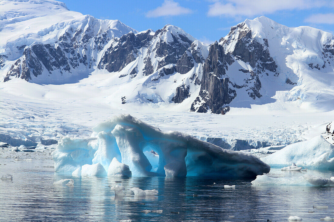 Antarktis; antarktische Halbinsel; bei Yalour Island; Schnee bedeckte Gebirge; im Vordergrund türkis leuchtender Eisberg