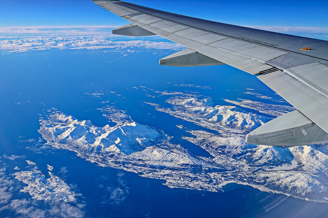 Blick auf Flugzeugflügel und norwegische Küste mit verschneiten Inseln, nahe Tromsö, Troms og Finnmark, Norwegen