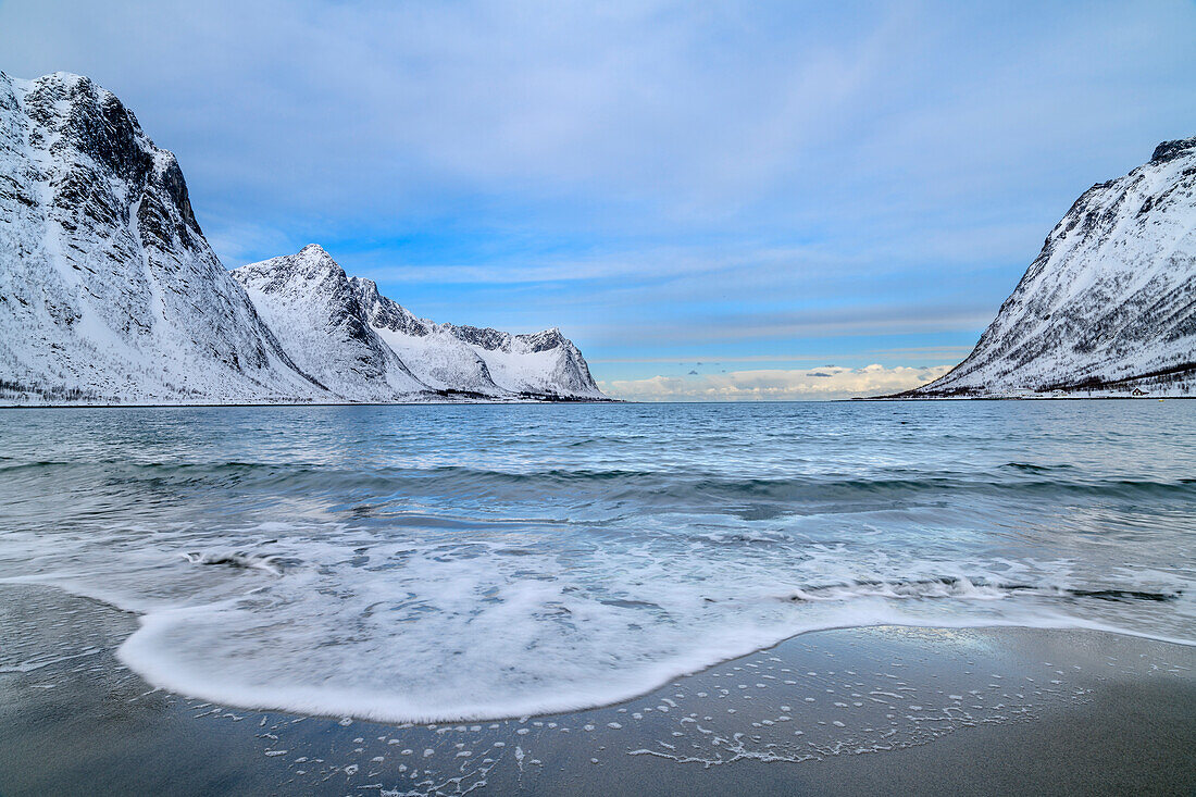 Steinfjord beach with incoming wave and snowy mountains in the background, Steinfjord, Senja, Troms og Finnmark, Norway