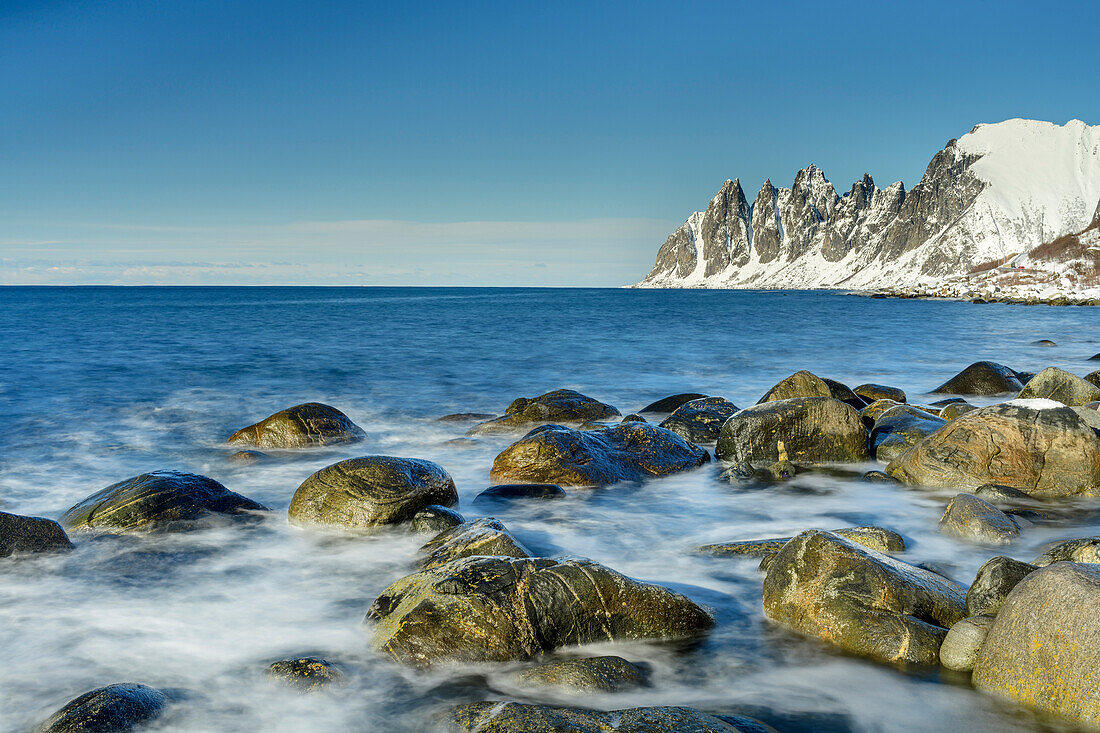 Surf washes over boulders with Devil's Teeth in background, Ersfjord, Senja, Troms og Finnmark, Norway