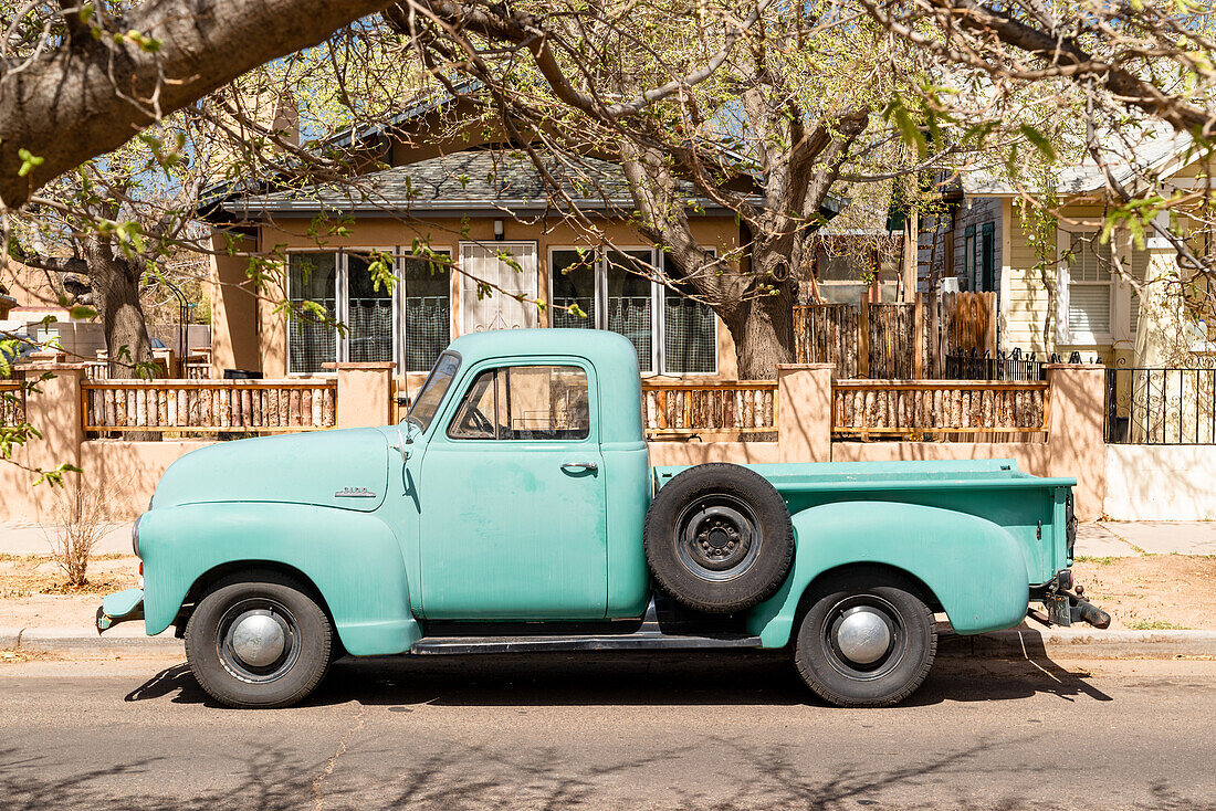 Sun bleached green oldtimer pick up truck parked in the streets of Albuquerque, New Mexico.