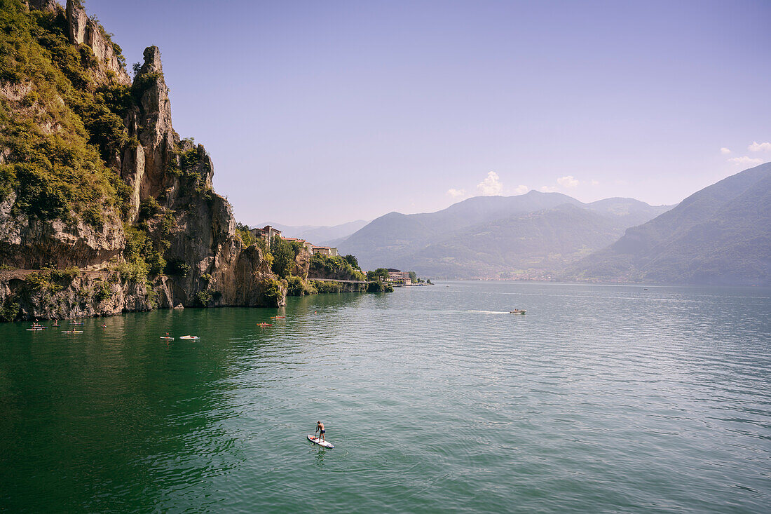 numerous standup paddlers (SUP) on the rugged cliffs of Lake Iseo (Lago d'Iseo, also Sebino) near Castro, Brescia and Bergamo, Northern Italian Lakes, Lombardy, Italy, Europe