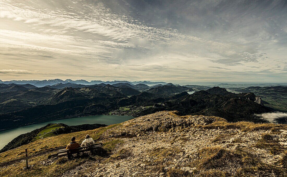 Couple on a bench on the Schafberg with a view over Lake Wolfgangsee and the Alpine mountains, Salzkamergut, Alps, Austria