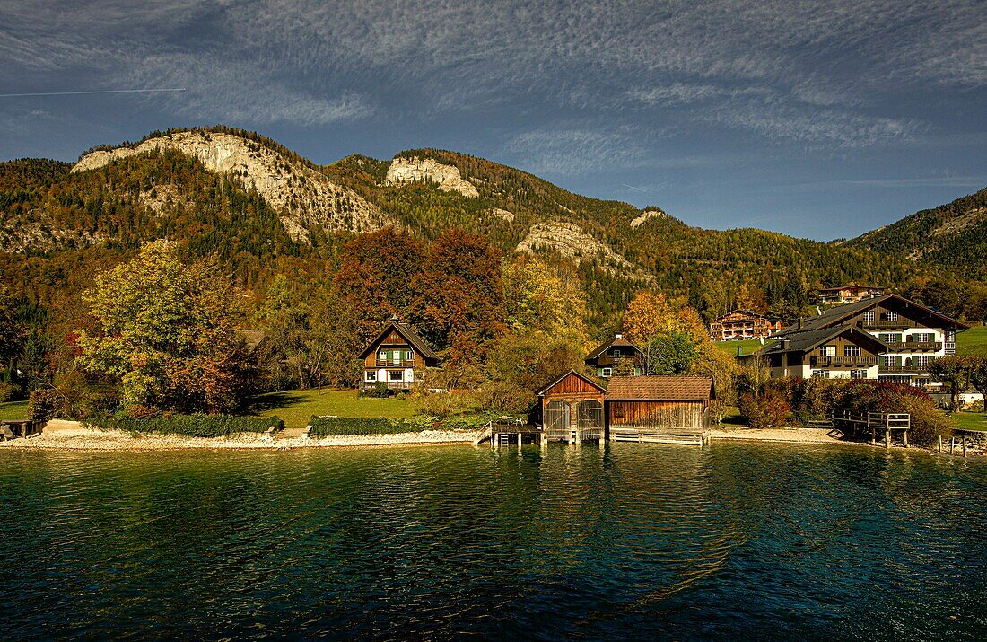 Blick vom Wolfgangsee auf Alpenhäuser und Bootshäuser am Seeufer, im Hintergrund die Berge des Salzkammerguts, Österreich