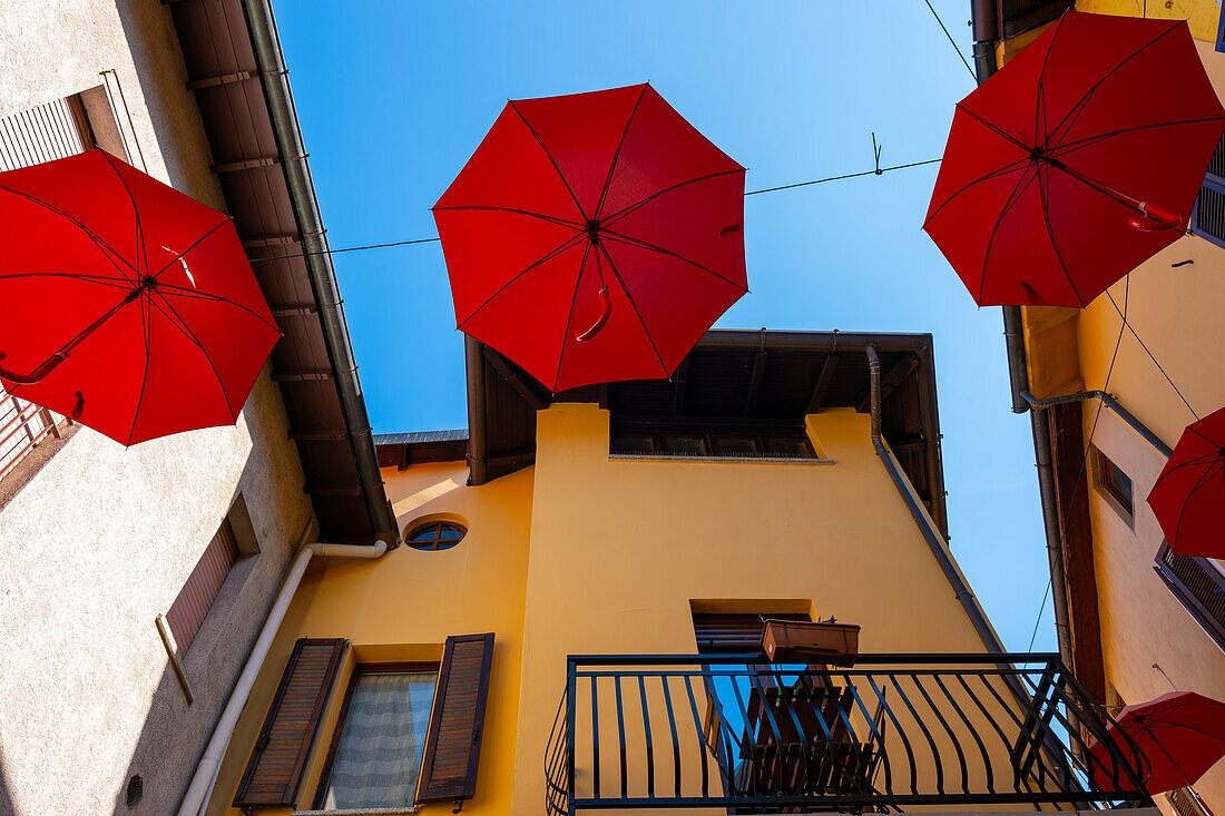 City Street in Porto Ceresio with Hanging Umbrellas in a Sunny Summer Day in Porto Ceresio, Lombardy, Italy.