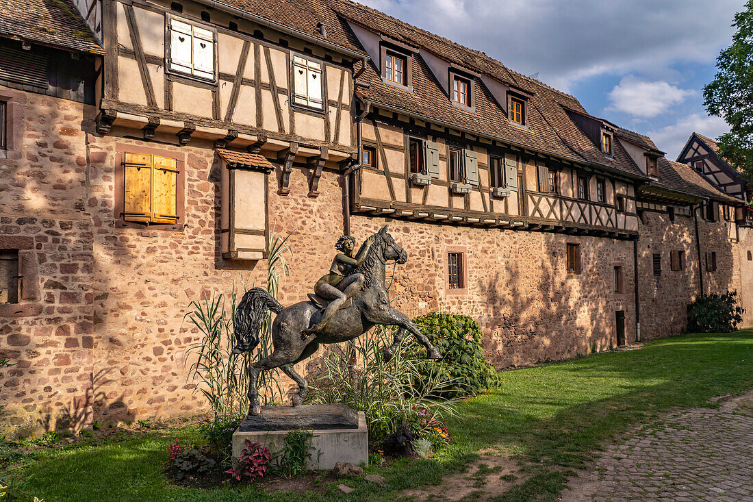 Statue einer reitenden Frau mit Pferd La Dame du Parc vom Künstler Josepha und Fachwerkhäuser der Stadtmauer von Riquewihr, Elsass, Frankreich