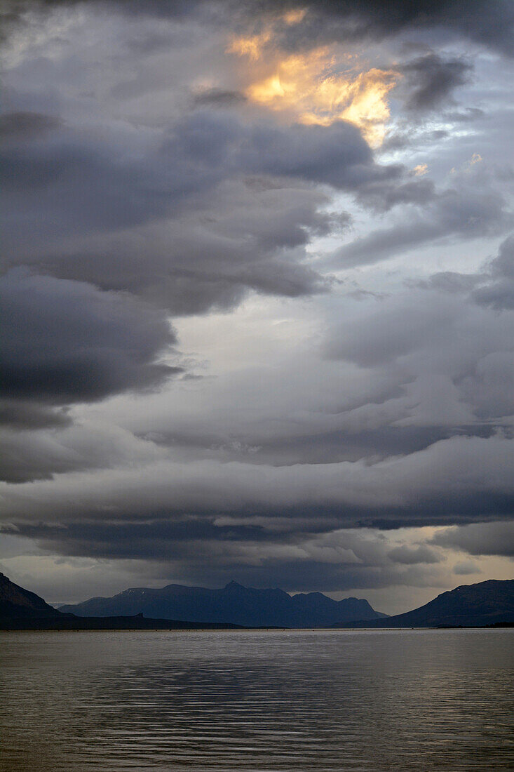 Chile; Südchile; Region Magallanes; Puerto Natales; Seno de Ultima Esperanza; im Hintergrund die Gebirge der südlichen Cordillera Patagonica; Sonne und dunkle Regenwolken