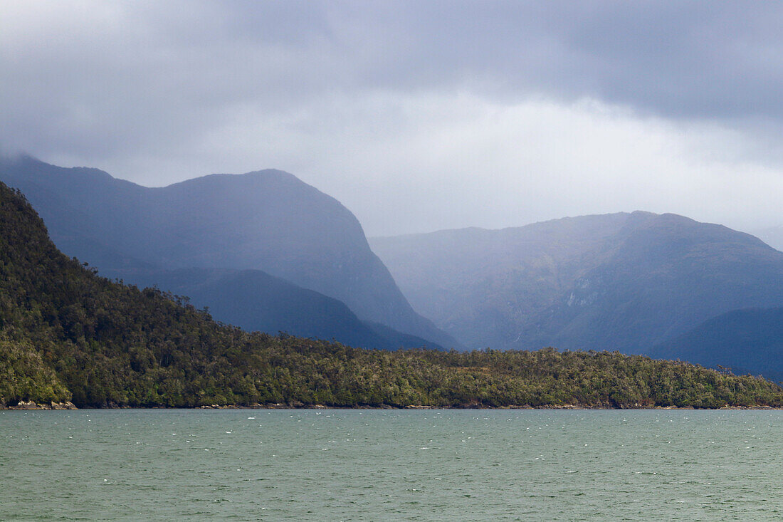 Chile; Südchile; Region Magallanes; Gebirge der südlichen Cordillera Patagonica; auf der Navimag Fähre durch die patagonischen Fjorde; Canal Messier; Sonnenstrahlen durchbrechen die Regenwolken