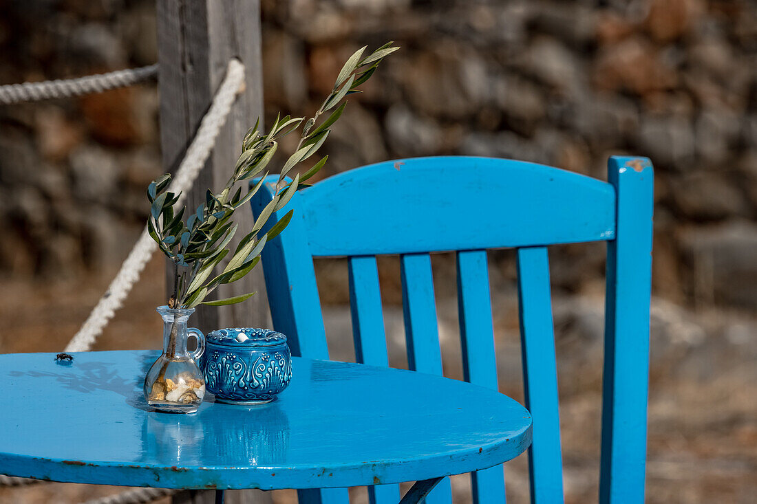 Vase mit Olivenbaumzweig auf einem blauen Tisch in Griechenland