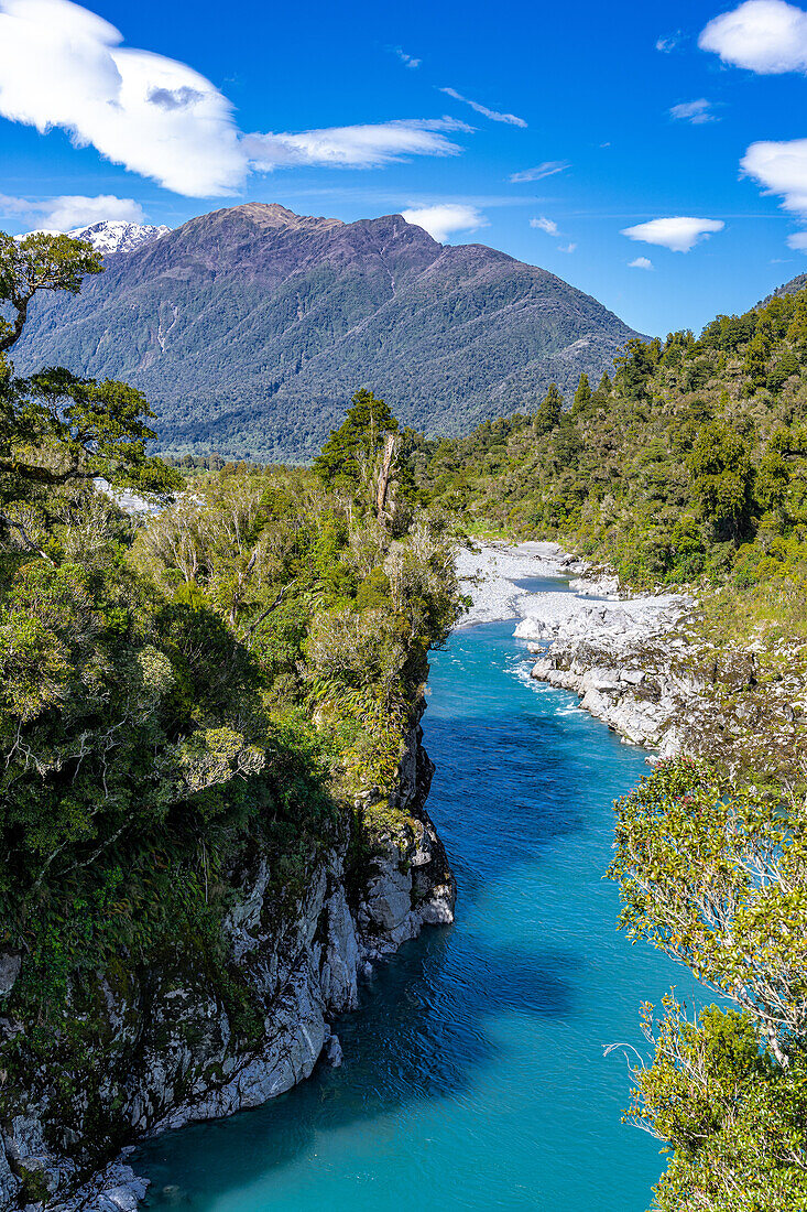 Turquoise waters flow through the Hokitika Gorge amidst lush vegetation and rock formations.