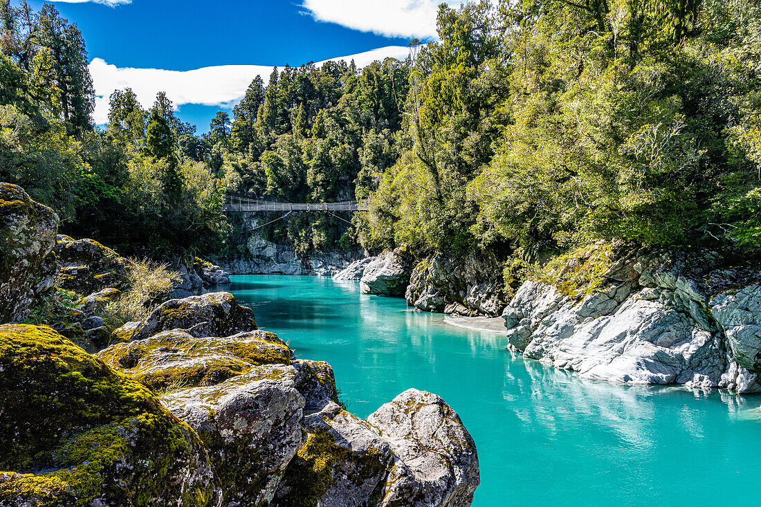 Turquoise waters flow through the Hokitika Gorge amidst lush vegetation and rock formations.