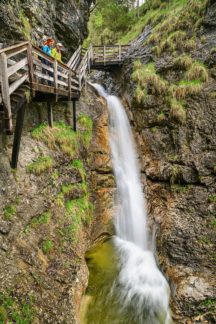 Mann und Frau wandern durch Strohwollner Schlucht und blicken auf Wasserfall, Strohwollner Schlucht, Route der Klammen, Berchtesgadener Alpen, Salzburg, Österreich