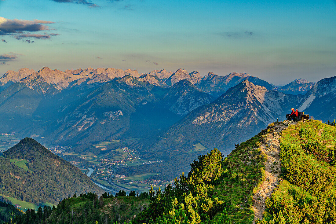Zwei Personen beim Wandern sitzen auf Aussichtsbank und blicken auf Karwendel und Inntal, von der Gratlspitze, Wildschönau, Kitzbüheler Alpen, Tirol, Österreich 