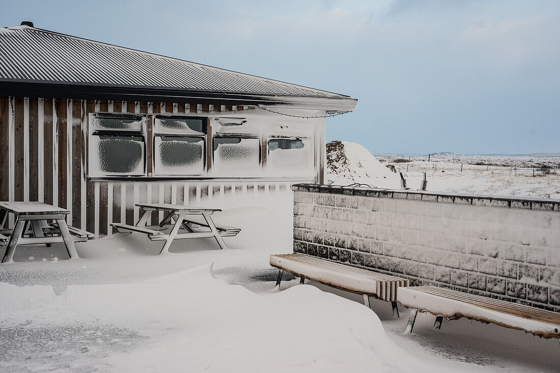 Eingeschneite Hütte und Sitzbänke, Island im Winter