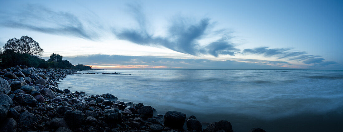 Steinküste an der Ostsee kurz vor Sonnenaufgang, bizarre Wolken, Morgenrot am Horizont, Insel Mön, Dänemark