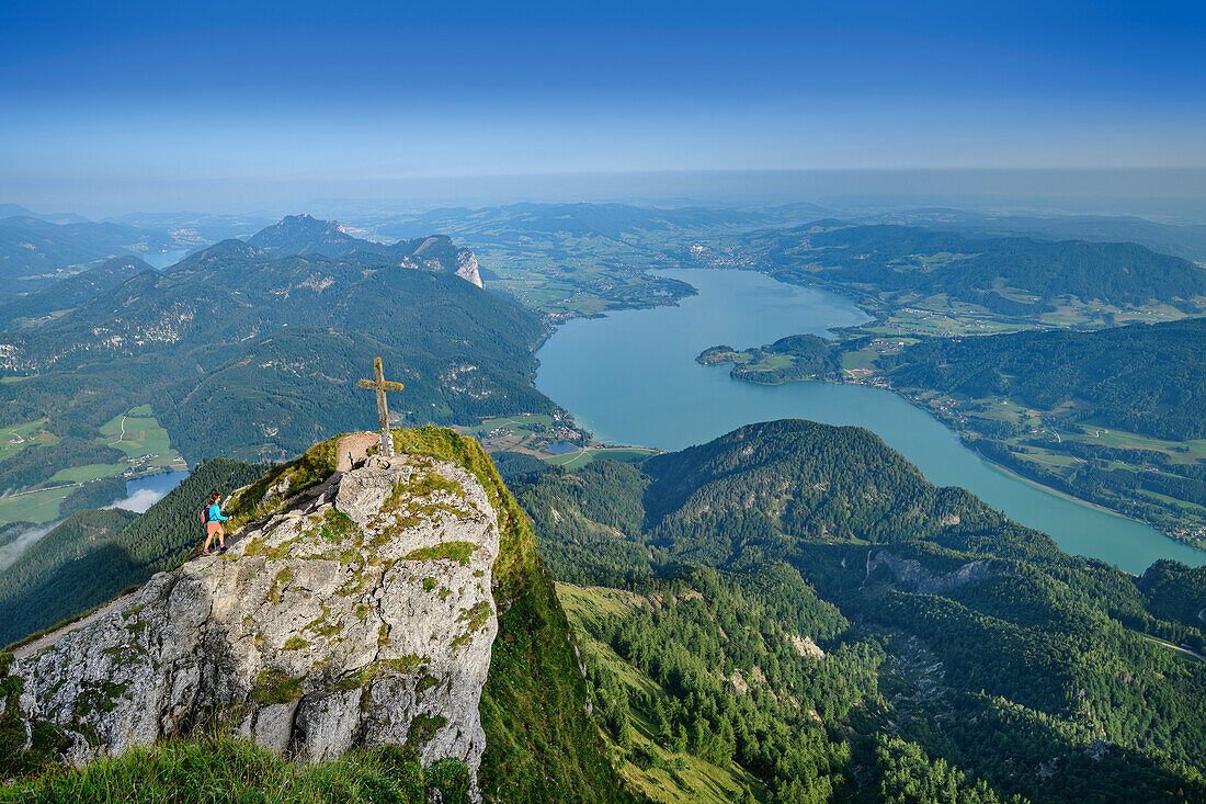 Frau beim Wandern geht auf Gipfelkreuz an der Himmelspforte zu, Mondsee im Hintergrund, Himmelspforte, Schafberg, Salzkammergutberge, Salzkammergut, Oberösterreich, Österreich