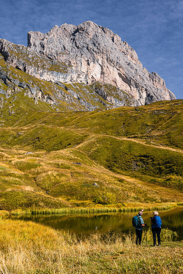 Wanderer vor einem See vor der Odlegruppe, Seceda im Herbst, Grödnertal, Bozen, Südtirol, Italien