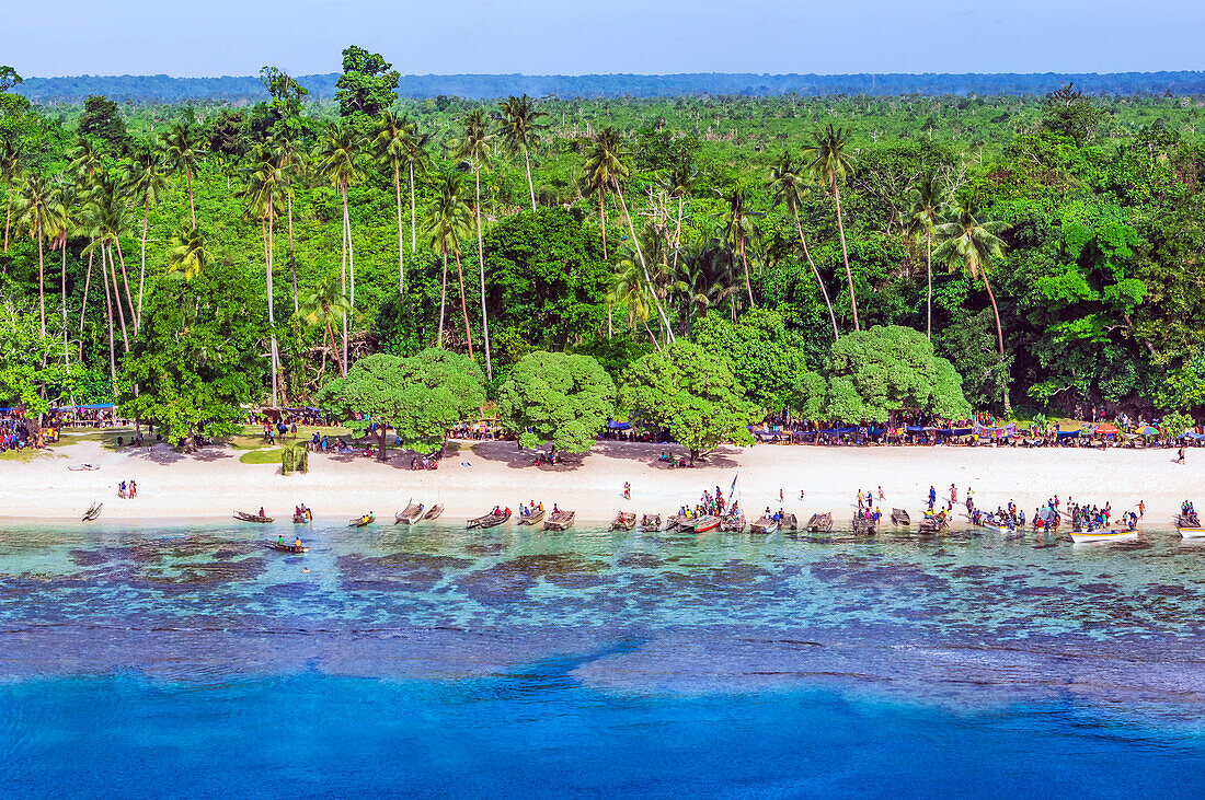 Menschen am Strand mit Booten vor Palmenwald auf den Conflict-Inseln (auch Conflict Atoll), ein Atoll in der Salomonensee, Provinz Milne Bay, Papua-Neuguinea, Melanesien, Südsee