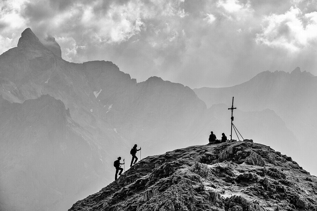 Two women climb to the summit of the Rötelstein, Dachstein group in the background, at Rötelstein, Dachstein, Salzburg, Austria