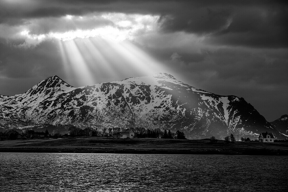 Sonnenstrahlen scheinen durch Wolkenloch auf Berge und Fjord, Skreda, Lofoten, Nordland, Norwegen