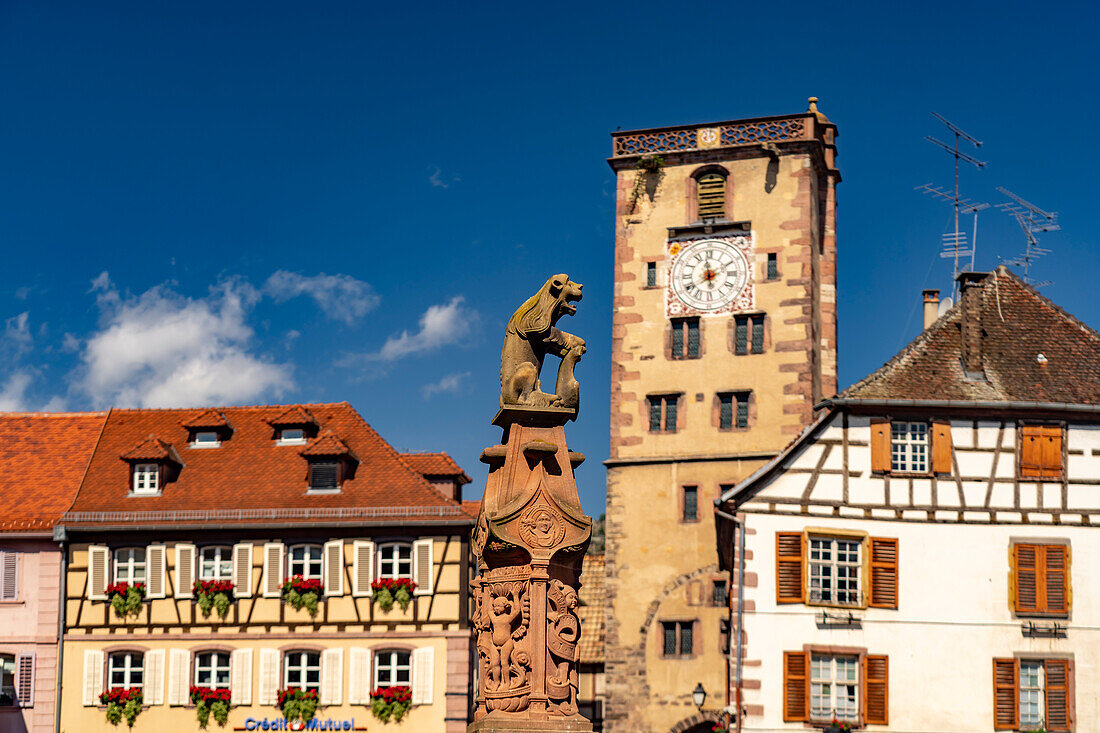 Löwe mit Stadtwappen am Marktbrunnen vor dem Rathaus und der Metzgerturm in Ribeauville, Elsass, Frankreich 