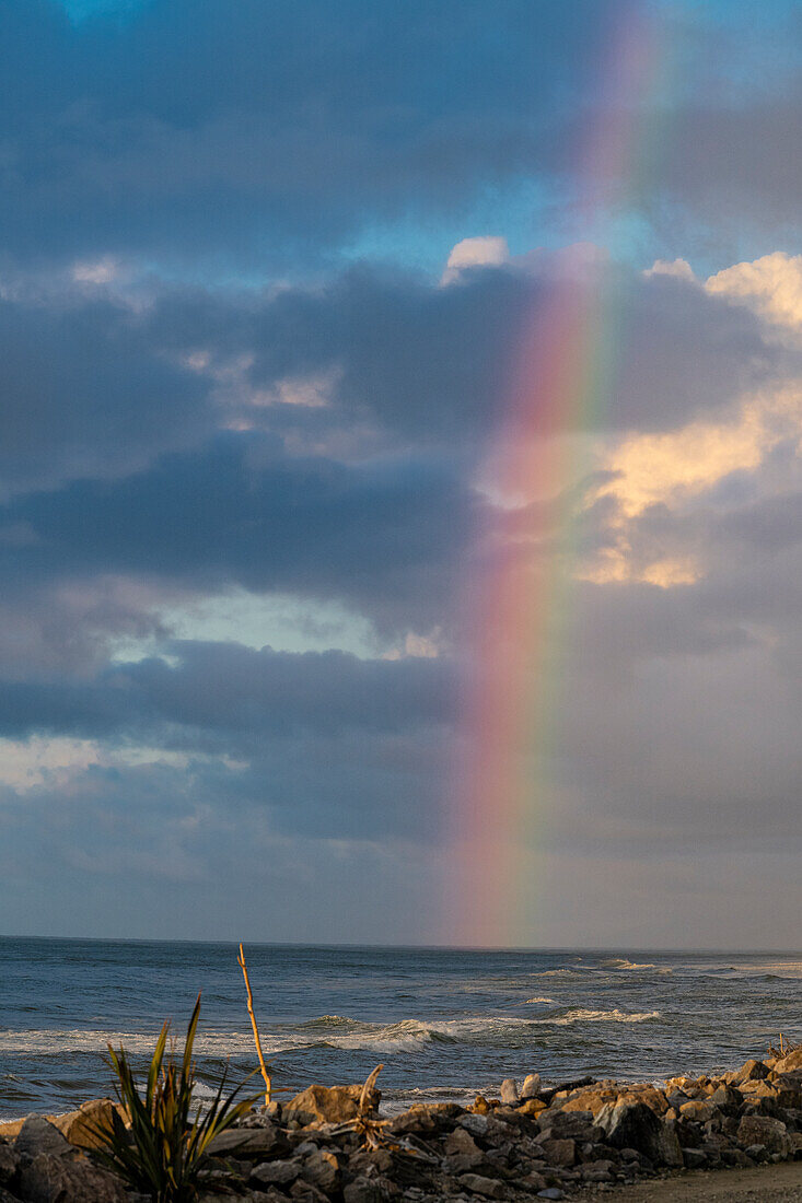 Rainbow over the Tasman Sea Beach following a storm in Hokitika New Zealand