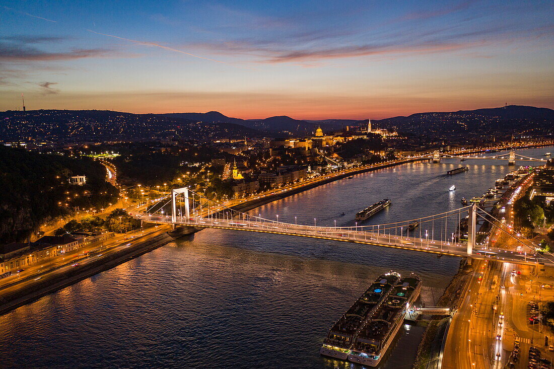 Aerial view of river cruise ships moored on Danube river with bridges, Buda Castle and Fishermen's Bastion at dusk, Budapest, Pest, Hungary, Europe