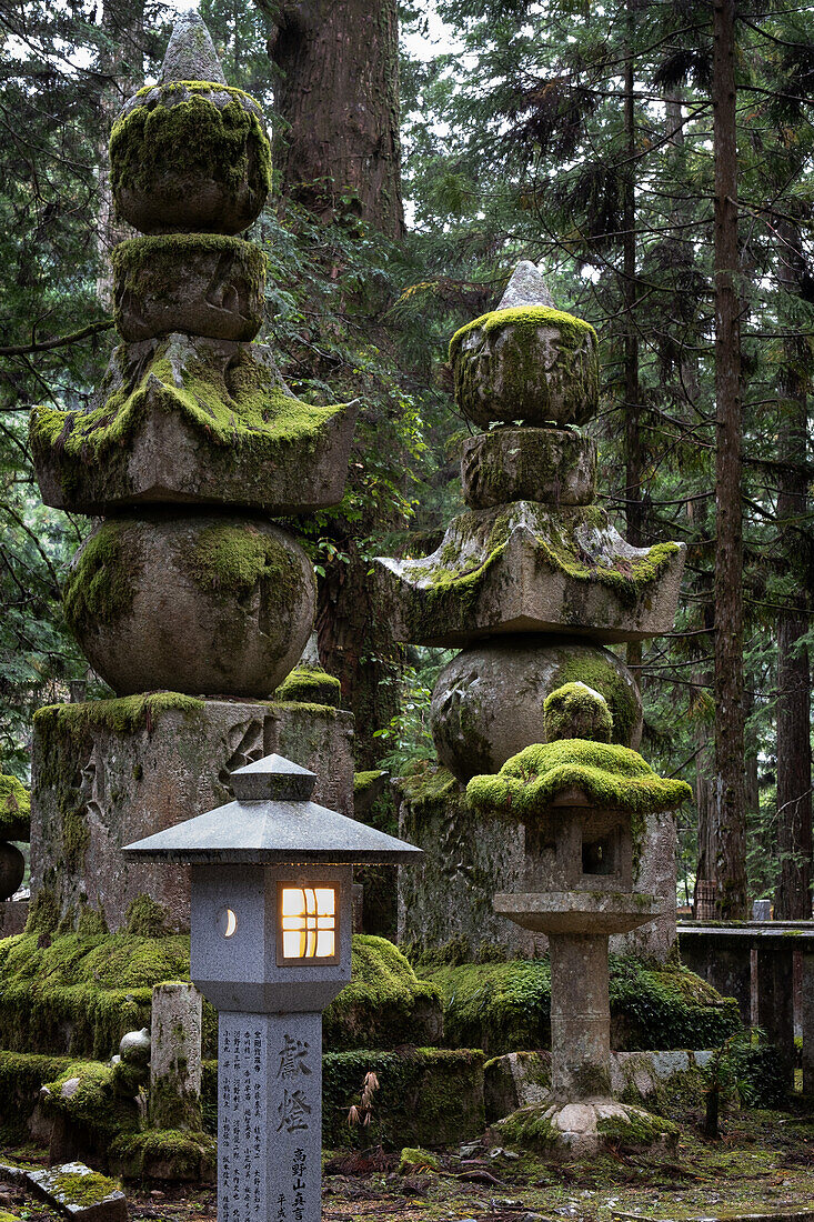 Blick auf Laternen und moosige Grabsteine im Friedhof Okunoin, Okuno-in, Koyasan, Koya, Ito District, Wakayama, Japan