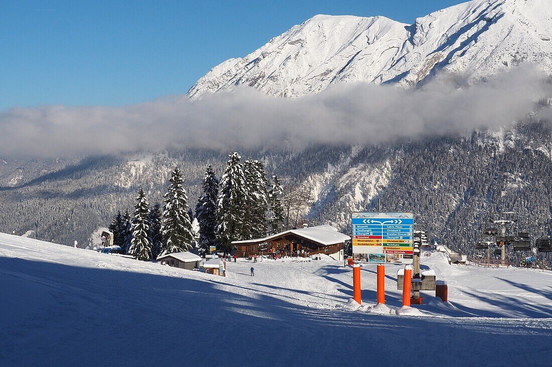 Skifahrer auf Piste vor Wegweisern, Sessellift und Hütte, Skigebiet Christlum bei Achenkirch, Achensee, Tirol, Österreich