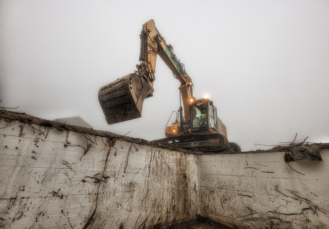 Bagger in Aktion vor einer Grube auf einer Baustelle, Schweiz