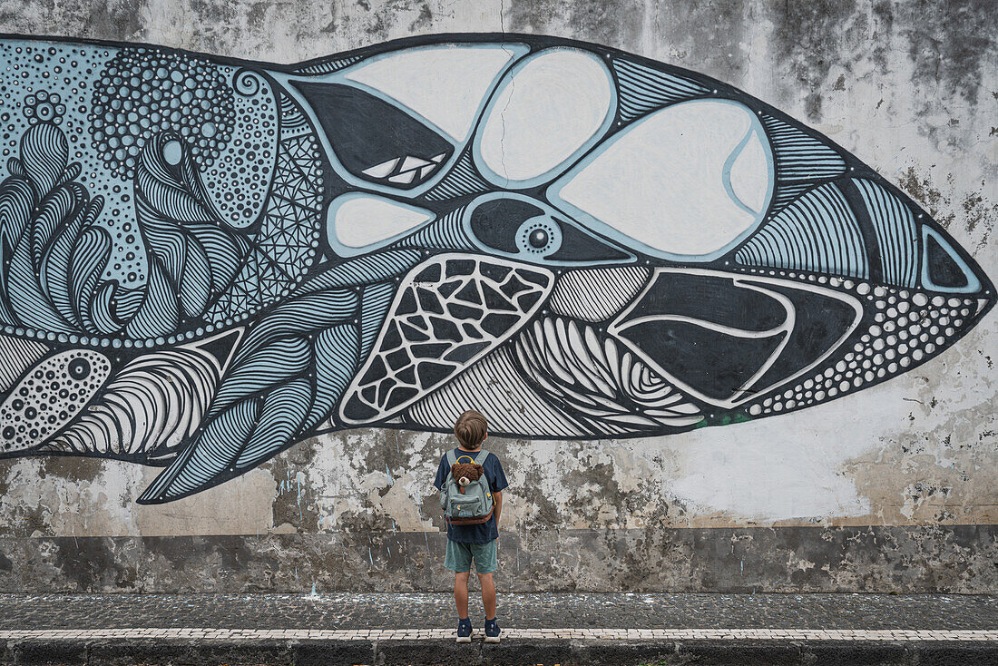 Kleiner Junge starrt auf ein Wandgemäde von einem Wal in den Straßen von Ponta Delgada, Sao Miguel, Azoren